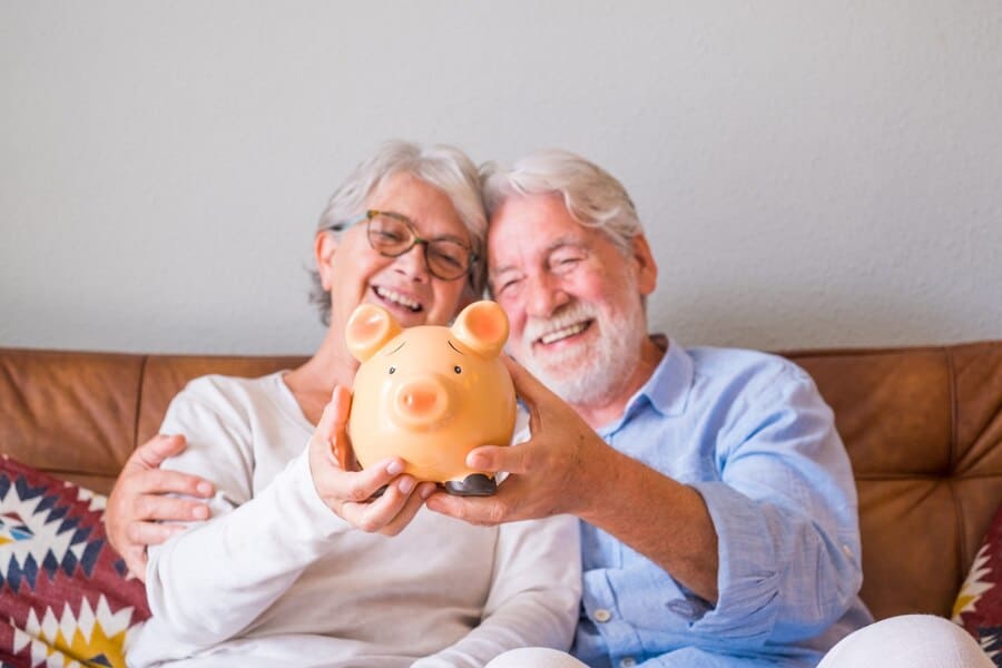 זוג מבוגרים חוסכים עם משכנתא פנסיונית ומחזיקים קופת חסכון בצורת חזיר